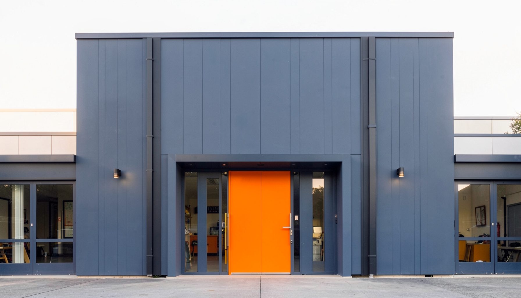 Clean symmetrical architectural photograph of a workshop facade in soft navy and warm light tones, conveying a calm professional mood